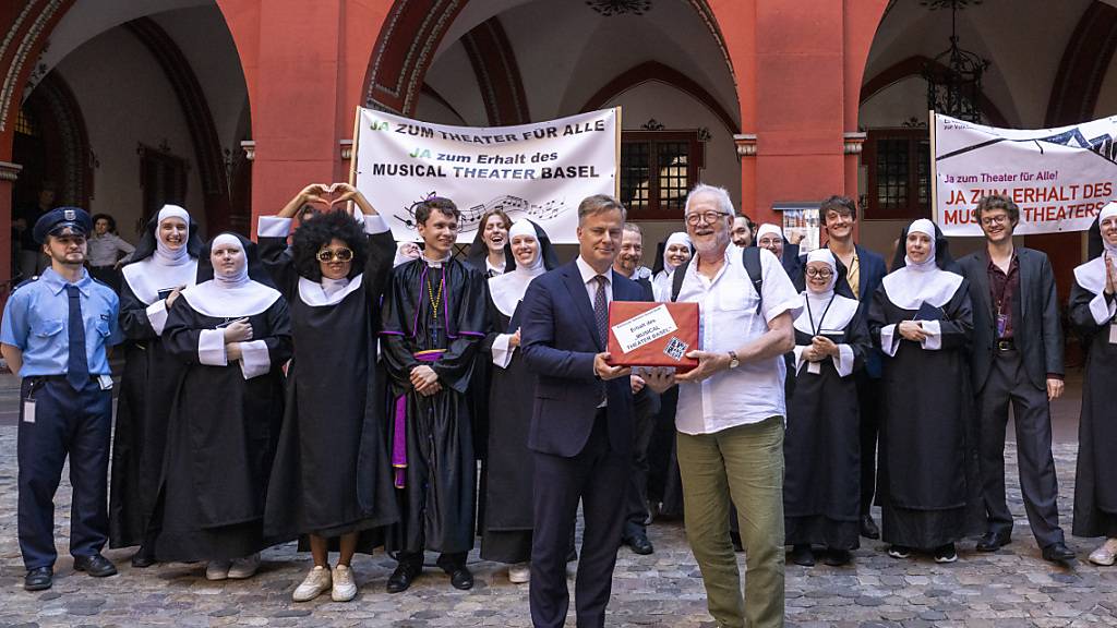 Toni Kleimann (vorne rechts), Initiant des Volksbegehrens zum Erhalt des Musical Theater Basel, übergibt in Begleitung des Musical-Ensembles «Sister  Act» dem Basler Vizestaatsschreiber Marco Greiner die Unterschriften.