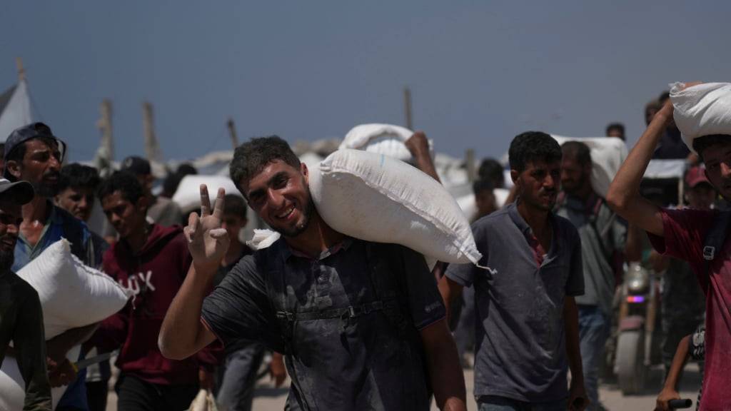 Palästinenser tragen Mehlsäcke, die von einem humanitären Hilfskonvoi abgeladen wurden. Foto: Abdel Kareem Hana/AP/dpa