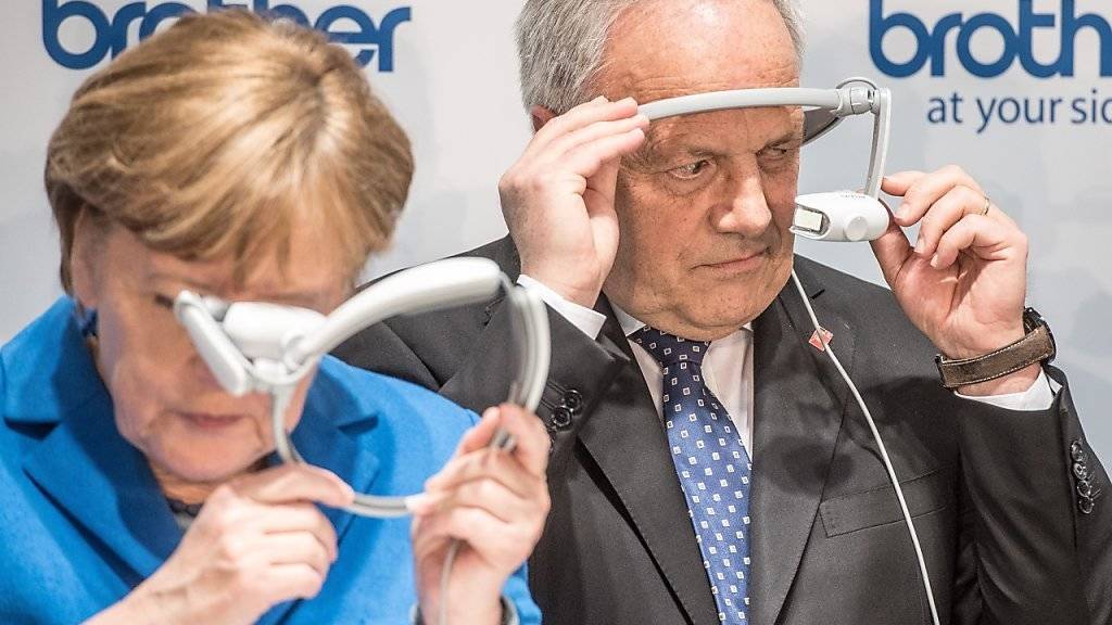 Angela Merkel und  Johann Schneider-Ammann schauen an der CeBIT durch Augmented-Reality-Brillen.