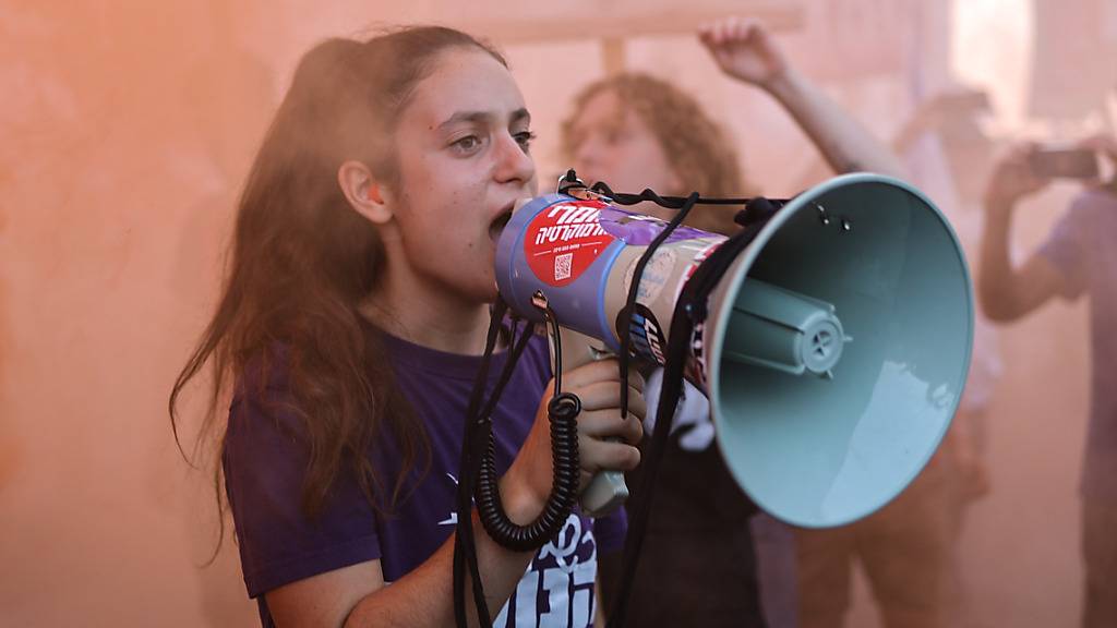 Eine israelische Demonstrantin ruft bei einer Demonstration vor dem Obersten Gerichtshof Slogans in ein Megafon, die sich gegen die geplante Justizreform der Regierung von Premierminister Netanjahu richten. Israels Oberstes Gericht will sich am Dienstag mit dem höchst umstrittenen Justizumbau der rechts-religiösen Regierung befassen. Foto: Ilia Yefimovich/dpa