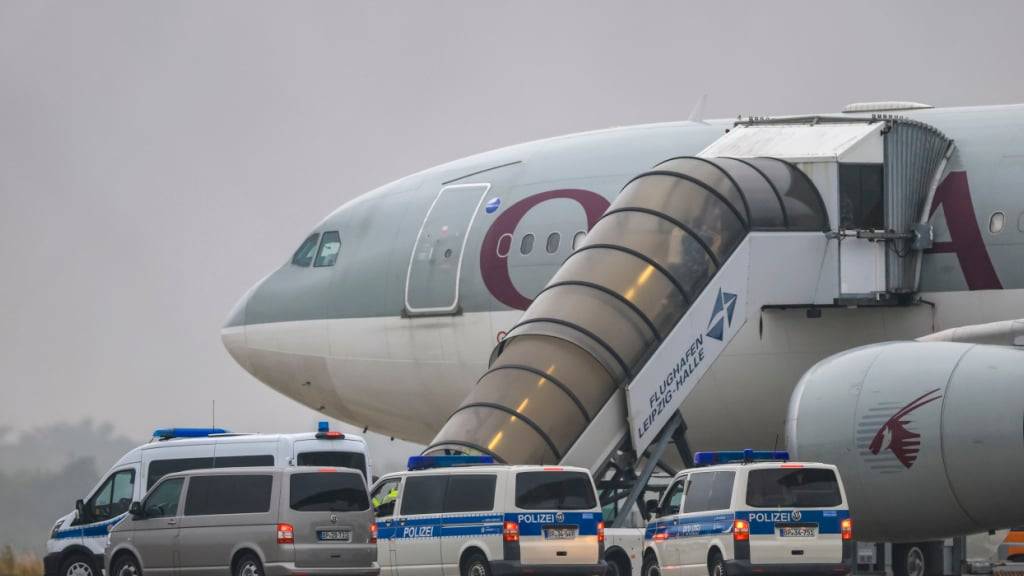 dpatopbilder - Menschen besteigen ein Flugzeug der Qatar Airways, vor dem Fahrzeuge der Bundespolizei stehen, auf dem Vorfeld am Flughafen Leipzig/Halle. Foto: Jan Woitas/dpa