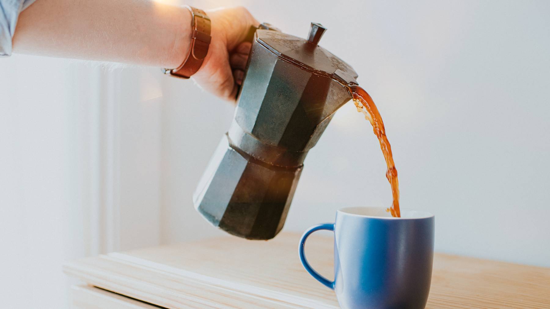 Kaffee wird in blaue Tasse gegossen.