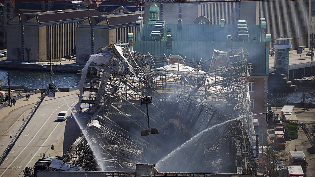 Einsatzkräfte arbeiten daran, das Feuer vollständig zu löschen und das Gebäude der ehemaligen Börse von Kopenhagen zu sichern. Ein Feuer wütete am Vortag in dem Bau, einem der ältesten Gebäude Kopenhagens, und verursachte den Einsturz des ikonischen Turms der Alten Börse aus dem 17. Jahrhundert. Foto: Liselotte Sabroe/Ritzau Scanpix Foto/AP/dpa