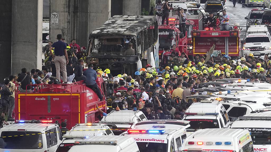 Rettungskräfte sind in einem Vorort von Bangkok im Einsatz an der Stelle, an der ein Bus in Brand geraten war, in dem junge Schüler saßen. Foto: Sakchai Lalit/AP/dpa