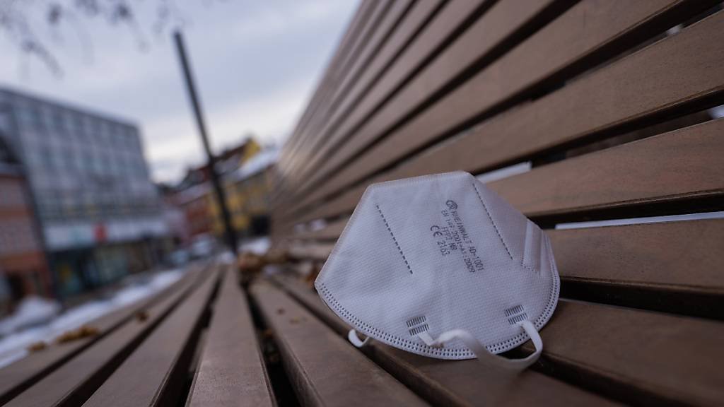 Eine FFP2-Maske liegt auf einer Parkbank. Foto: Nicolas Armer/dpa