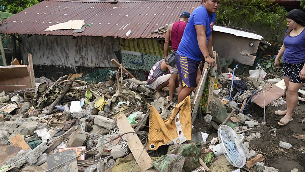 Bewohner sammeln Habseligkeiten aus ihren zerstörten Häusern nach einem durch den Tropensturm Trami ausgelösten Erdrutsch in Talisay, Provinz Batangas, Philippinen. Foto: Aaron Favila/AP/dpa