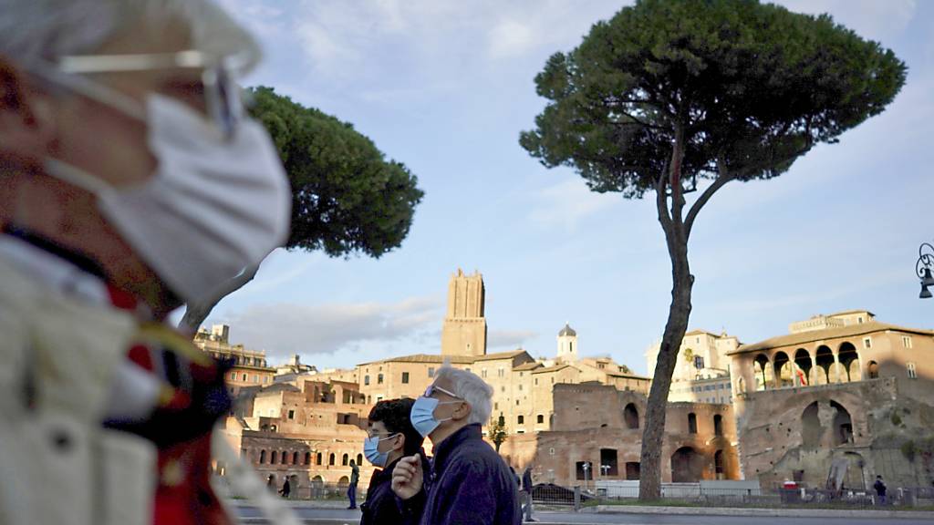 Passanten mit Mund-Nasen-Bedeckungen spazieren in Rom. Italiens Regierung hat die Schutzmaßnahmen während der Corona-Pandemie weiter verschärft. Foto: Andrew Medichini/AP/dpa