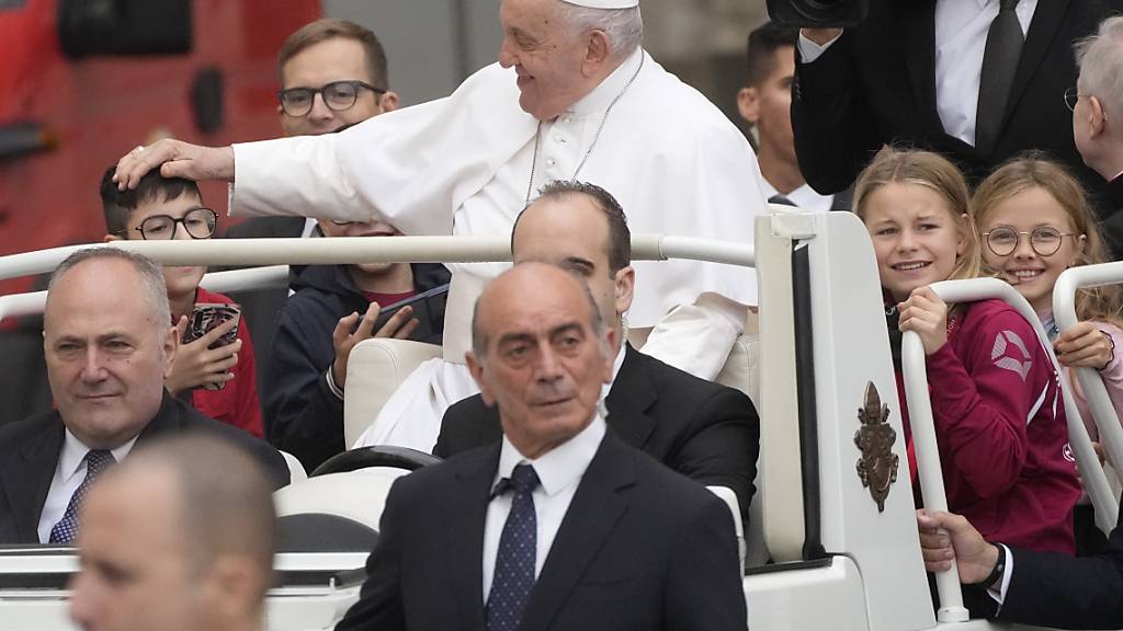 Papst Franziskus begrüßt Kinder in seinem Papamobil, als er zu seiner wöchentlichen Generalaudienz auf dem Petersplatz eintrifft. Foto: Gregorio Borgia/AP/dpa