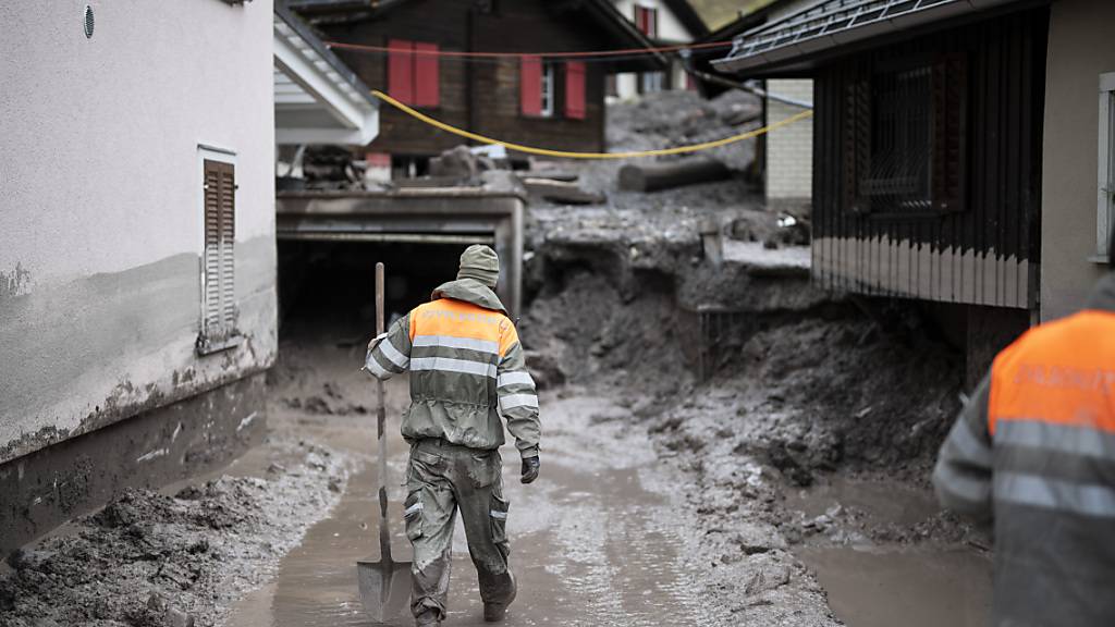 Zivilschützer schaufeln Schlamm aus dem vom Erdrutsch getroffenen Quartier im glarnerischen Schwanden.