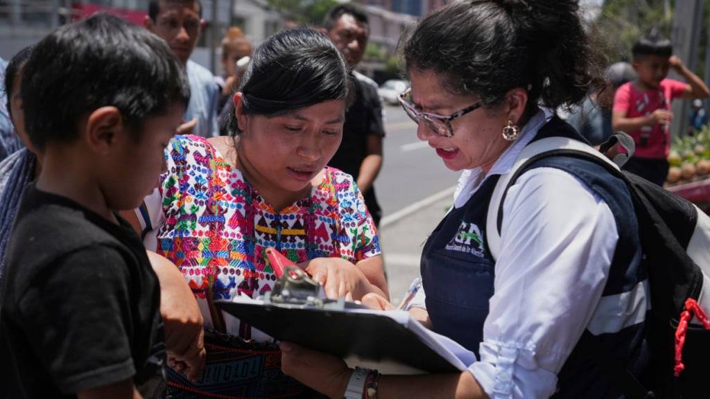 Eine Verwandte eines unbegleiteten Minderjährigen, der aus den Vereinigten Staaten überführt wurde, studiert vor dem internationalen Flughafen La Aurora in Guatemala-Stadt die Liste der Rückgeführten. Foto: Moises Castillo/AP/dpa