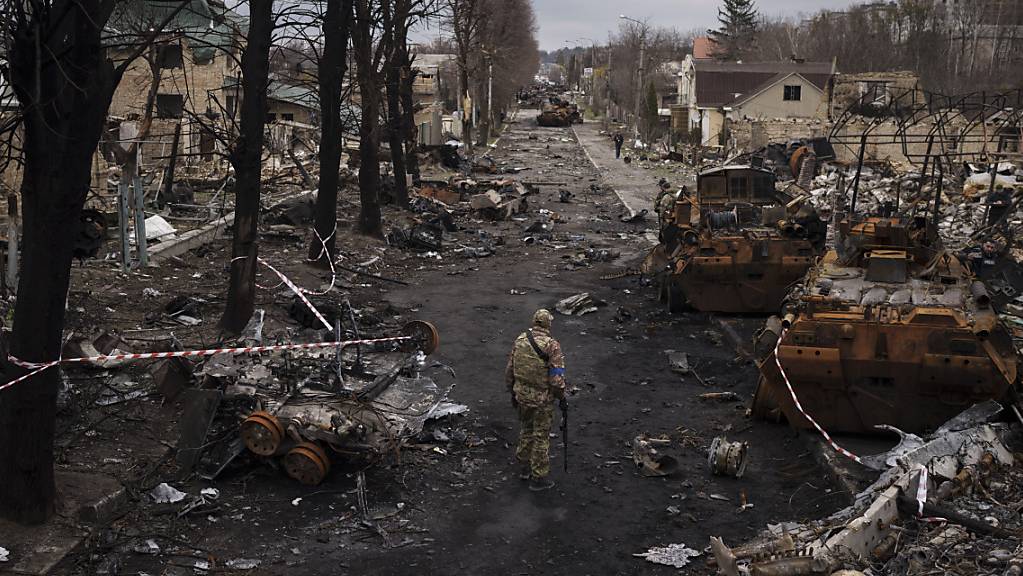 Ein ukrainischer Soldat steht neben zerstörten russischen Panzer in Butscha am Stadtrand von Kiew. Foto: Felipe Dana/AP/dpa