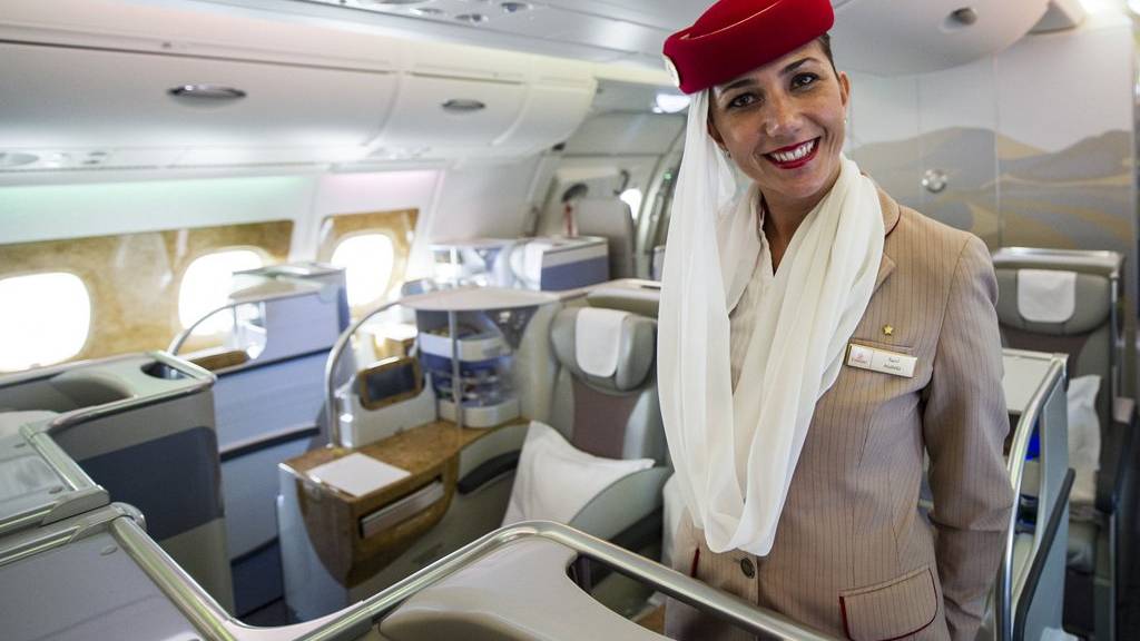 Eine Stewardess der Fluggesellschaft Emirates empfängt Passagiere freundlich.