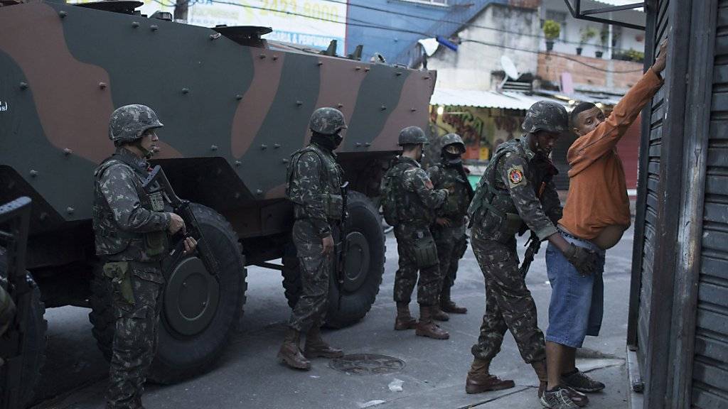 Soldaten durchsuchen während einer Razzia in einer Favela von Rio einen Einwohner.