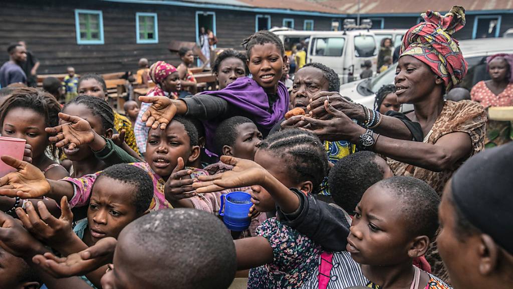 Menschen, die aus Goma geflohen sind, versammeln sich an einer Lebensmittelverteilungsstelle in Sake, wo sie Unterschlupf gefunden haben. In der Millionenstadt Goma spitzt sich die Lage am Vulkan Nyiragongo dramatisch zu. Fast eine halbe Million Menschen ist verzweifelt auf der Flucht. Foto: Moses Sawasawa/AP/dpa