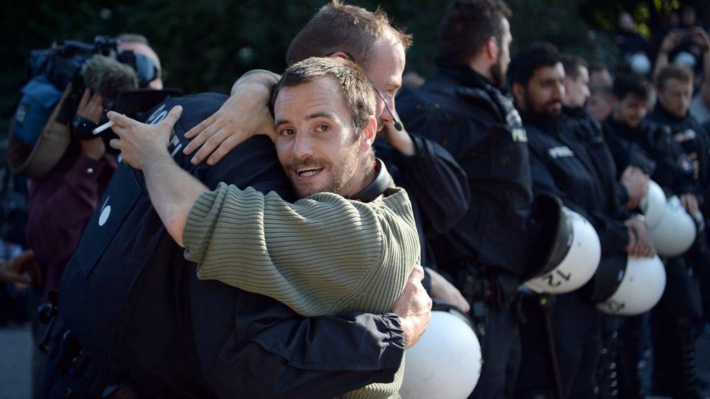 Unter Applaus von Demonstranten umarmen sich ein Demonstrant und ein Polizist am 08.07.2017 am Rande einer Sitzblockade. (Bild:KEYSTONE/DPA/Christophe Gateau)