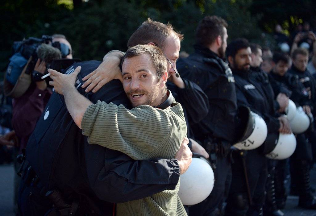 Unter Applaus von Demonstranten umarmen sich ein Demonstrant und ein Polizist am 08.07.2017 am Rande einer Sitzblockade. (Bild:KEYSTONE/DPA/Christophe Gateau)