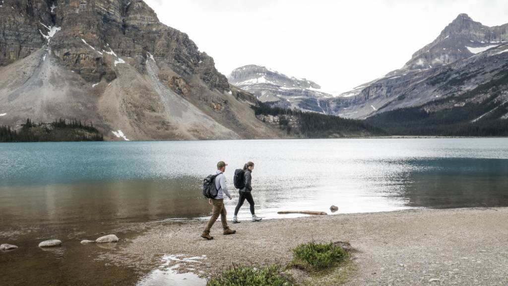 ARCHIV - Touristen spazieren um den Bow Lake in der Nähe der Bow Glacier Falls (im Hintergrund) in Alberta. Foto: Jeff Mcintosh/Canadian Press via ZUMA Press/dpa/Symbolbild - ACHTUNG: Nur zur redaktionellen Verwendung und nur mit vollständiger Nennung des vorstehenden Credits