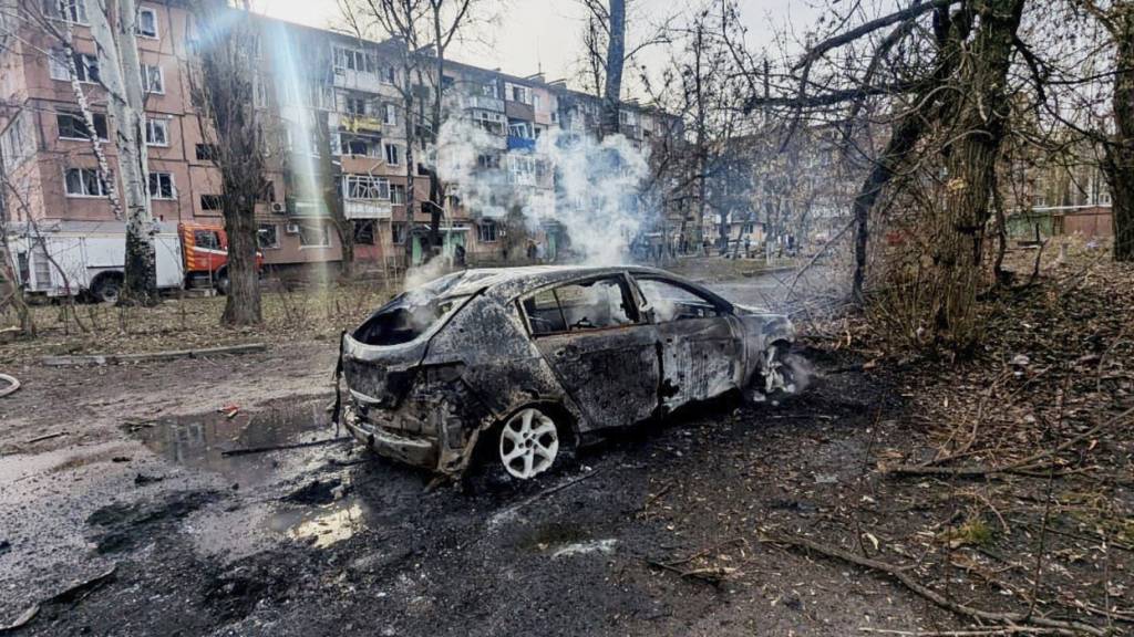 HANDOUT - Auf diesem vom ukrainischen Katastrophenschutz zur Verfügung gestellten Foto sind ein verbranntes Auto und beschädigte Wohnhäuser zu sehen, nachdem eine russische Rakete eingeschlagen ist. (Archivbild) Foto: Uncredited/Ukrainian Emergency Service/dpa
