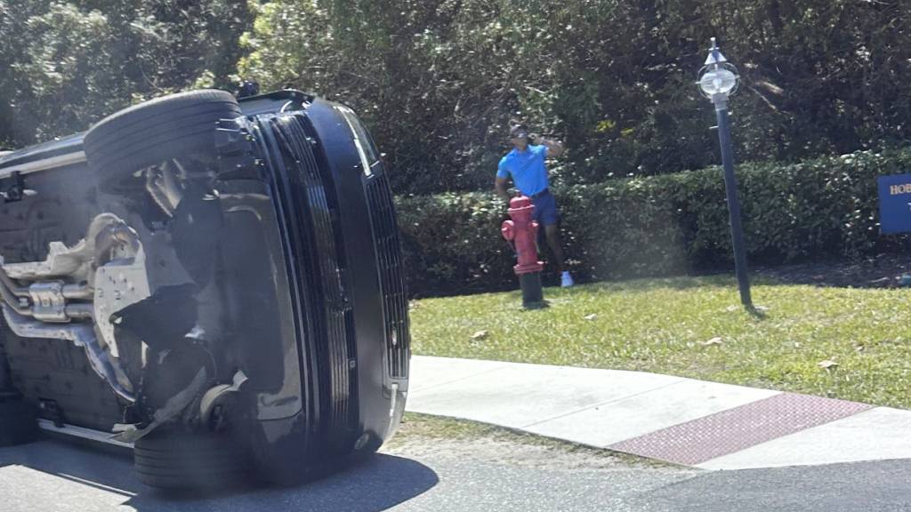 Nach dem Unfall steht Tiger Woods neben seinem auf der Seite liegenden Auto