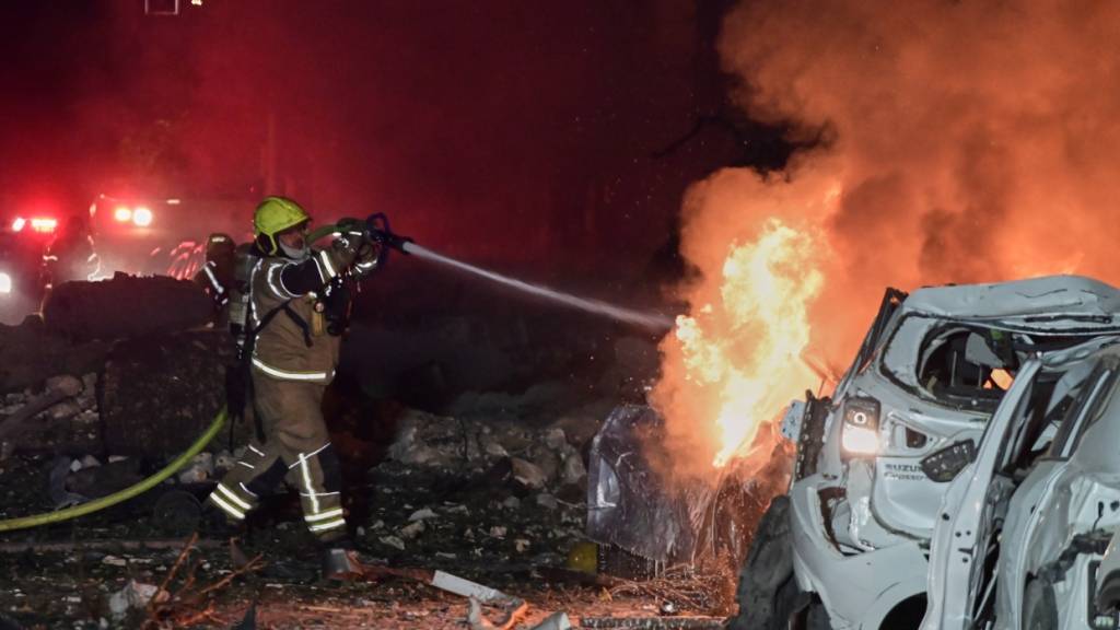 dpatopbilder - Ein Feuerwehrmann versucht, ein brennendes Auto an der Stelle zu löschen, an der eine iranische Rakete eingeschlagen ist, in Tel Aviv, Israel. Foto: Tomer Neuberg/AP/dpa
