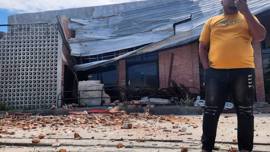 dpatopbilder - Ein Mann telefoniert mit seinem Handy in der Nähe eines durch ein Erdbeben beschädigten Gebäudes in Palu, Zentral-Sulawesi. Foto: Josua Marunduh/AP/dpa