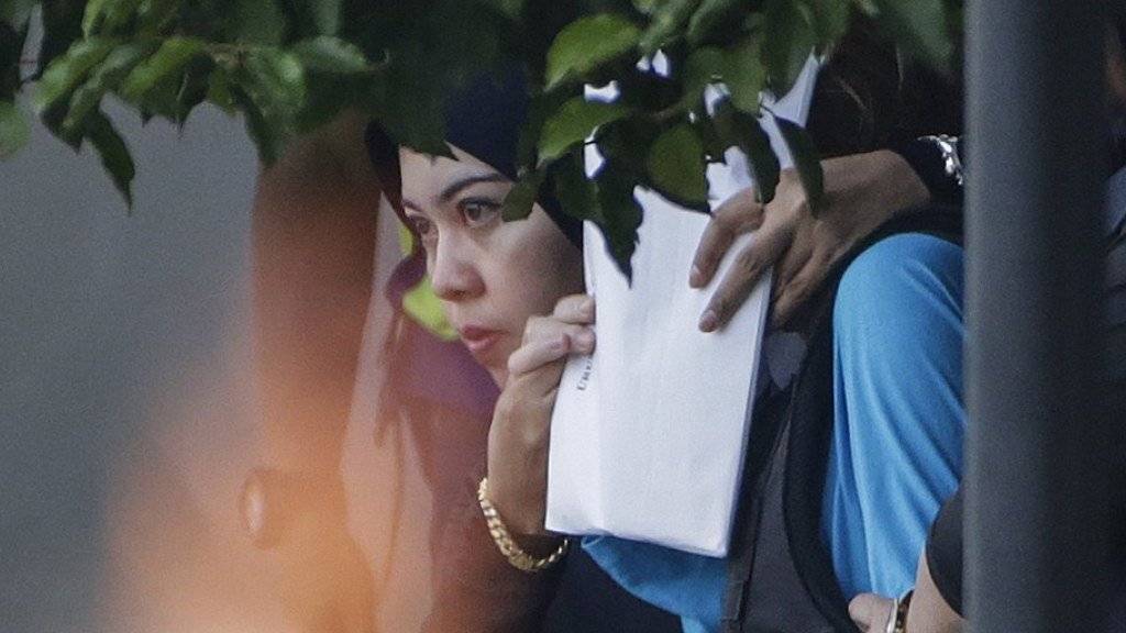 Die angeklagte Vietnamesin am Dienstag auf dem Weg ins Amtsgericht in Kuala Lumpur. Eine Polizistin deckt ihr Gesicht mit einem Papier ab.