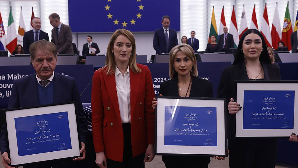 Saleh Nikbakht (l), Rechtsanwalt, der Familie von Jina Mahsa Amini, Afsoon Najafi (r) und Mersedeh Shahinkar (2.v.r), Frauenrechtlerinnen aus dem Iran und Roberta Metsola (2.v.l.), Präsidentin des Europäischen Parlaments stehen bei der Verleihung des Sacharow-Preises für geistige Freiheit 2023 während der Plenarsitzung des Europäischen Parlaments nebeneinander. Foto: Jean-Francois Badias/AP/dpa