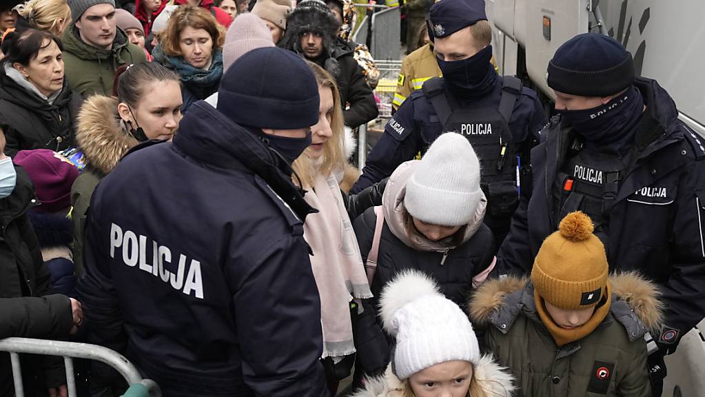 Flüchtlinge, die vor dem Krieg in der Ukraine geflohen sind, sammeln sich am Grenzübergang Korczowa in Polen. Nach Angaben Grenzschutzes sind in Polen seit dem Beginn des Kriegs in der Ukraine rund 964 000 ukrainische Flüchtlinge eingetroffen. Das teilte die Behörde am Sonntag per Twitter mit. Foto: Czarek Sokolowski/AP/dpa