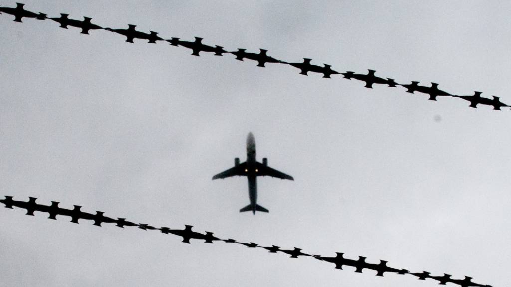 ARCHIV - Symbolbild: Ein Flugzeug ist hinter Stacheldraht zu sehen. Foto: Julian Stratenschulte/dpa