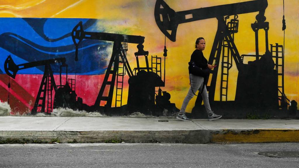 Passant geht an einem Wandgemälde mit Ölpumpen und -brunnen vorbei. Foto: Matias Delacroix/AP/dpa