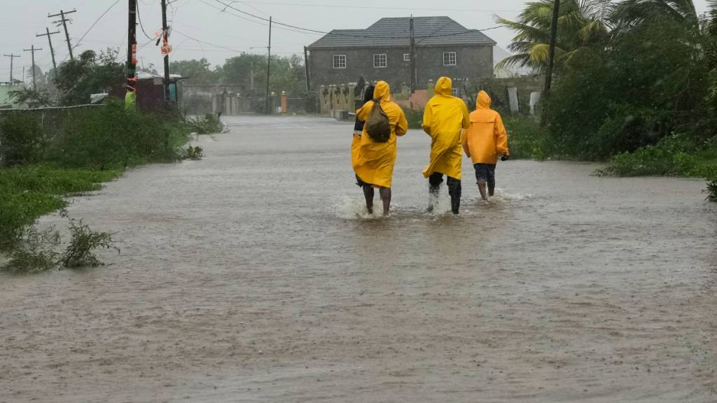 Menschen gehen während des Hurrikans Melissa in Rocky Point, eine Straße entlang. Foto: Matias Delacroix/AP/dpa