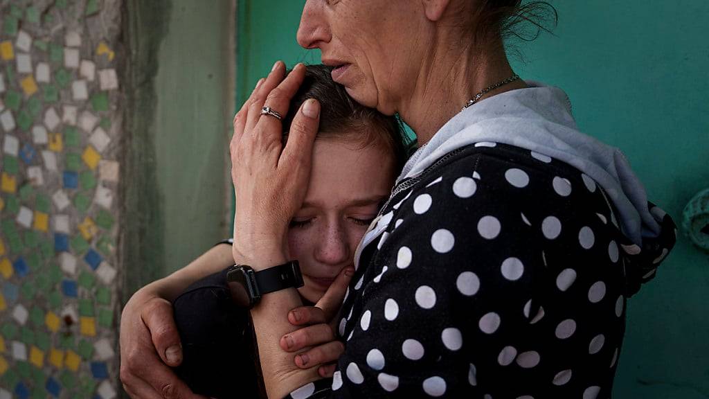Eine Mutter weint mit ihrer Tochter während der Trauerfeier für Maksym Martynenko, der bei einem russischen Angriff auf Sumy getötet wurde. Foto: Evgeniy Maloletka/AP/dpa