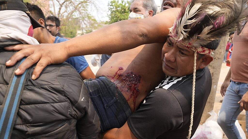 Indigene Demonstranten kommen einem anderen Demonstranten zu Hilfe, der bei Zusammenstößen mit der Polizei wegen der Verhaftung eines Stammesführers verletzt wurde. Foto: Jorge Saenz/AP/dpa