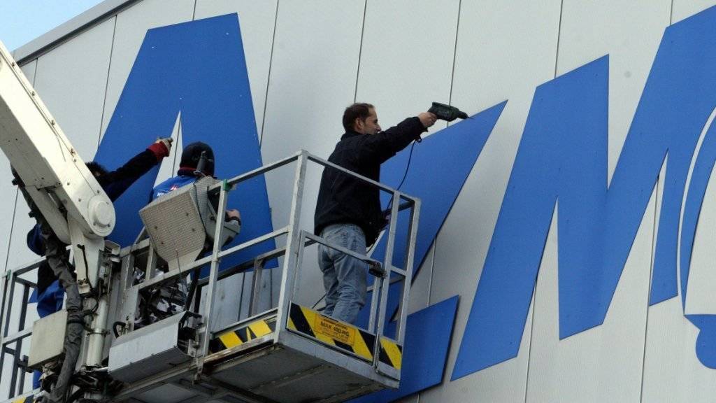 Arbeiter entfernen im März 2006 anlässlich der offiziellen Stabsübergabe der AZM an Emmi den Schriftzug AZM an der Fassade der Aargauer Zentralmolkerei in Suhr. (Archivbild)