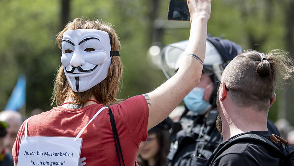 Demonstranten laufen mit einer «Guy Fawkes»-Maske auf der Straße des 17. Juni. Die Demonstranten protestieren gegen die Corona-Beschränkungen und die Änderung des Infektionsschutzgesetzes. Foto: Fabian Sommer/dpa