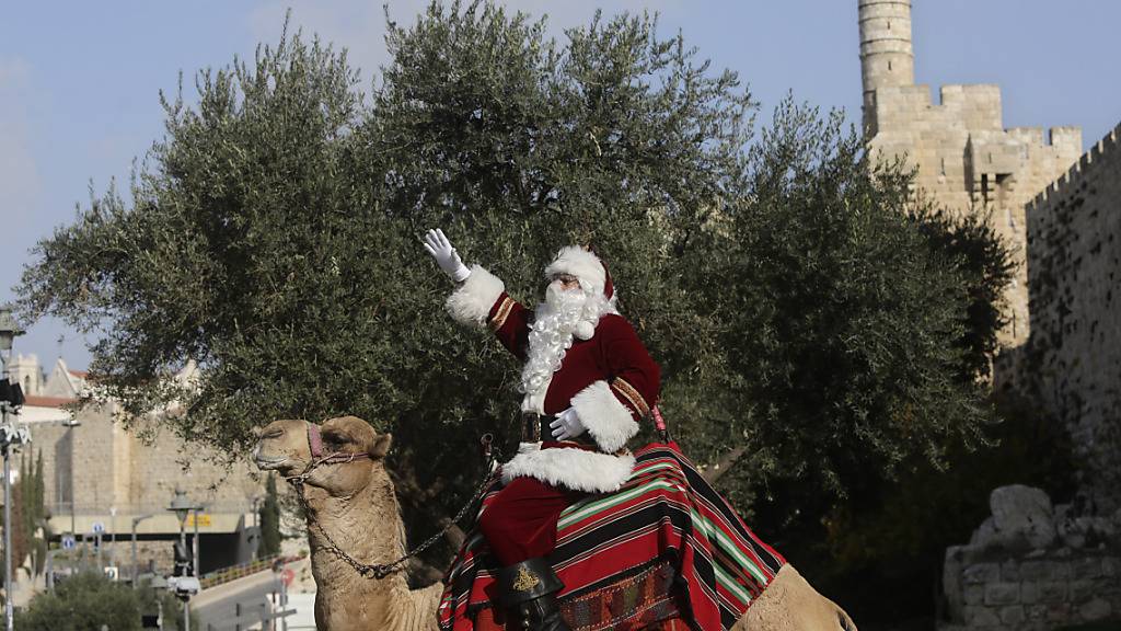 Ein Mann in einem Weihnachtsmann-Kostüm sitzt auf einem Kamel außerhalb der Altstadt von Jerusalem. Foto: Mahmoud Illean/AP/dpa