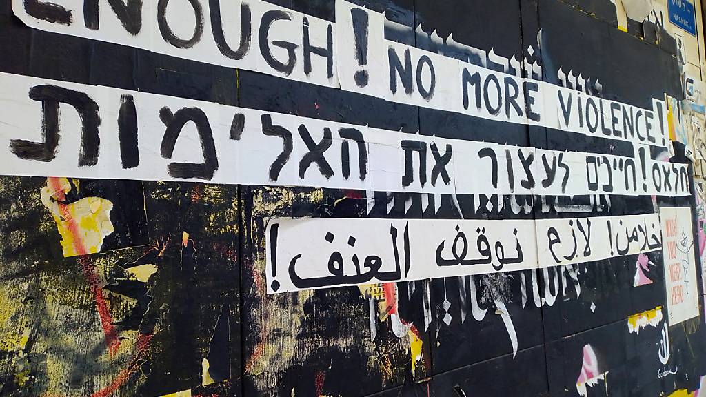 Graffiti gegen die Gewalt zwischen Juden und Arabern an einer Hauswand in englischer, hebräischer und arabischer Sprache. Zwei Rapper haben nach Ausschreitungen im Mai mit einem viral gegangenen Song die wechselseitigen Vorurteile thematisiert. Foto: Eva-Maria Krafczyk/dpa