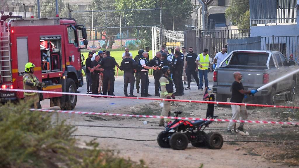 Israelische Polizisten und Feuerwehrleute arbeiten am Ort eines Raketenangriffs auf den israelisch kontrollierten Golanhöhen. Foto: Gil Eliyahu/AP/dpa