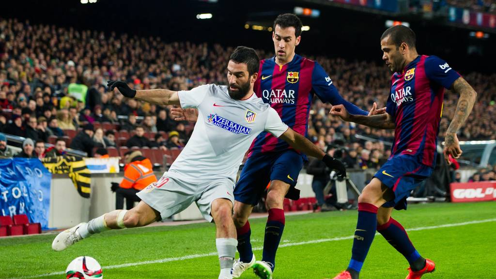 BARCELONA, SPAIN - JANUARY 21:  Arda Turan of Club Atletico de Madrid controls the ball next to Sergio Busquets (C) and Dani Alves (R) of FC Barcelona during the Copa del Rey Quarter-Final First Leg match between FC Barcelona and Club Atletico de Madrid at Camp Nou on January 21, 2015 in Barcelona, Spain. (Photo by Alex Caparros/Getty Images)