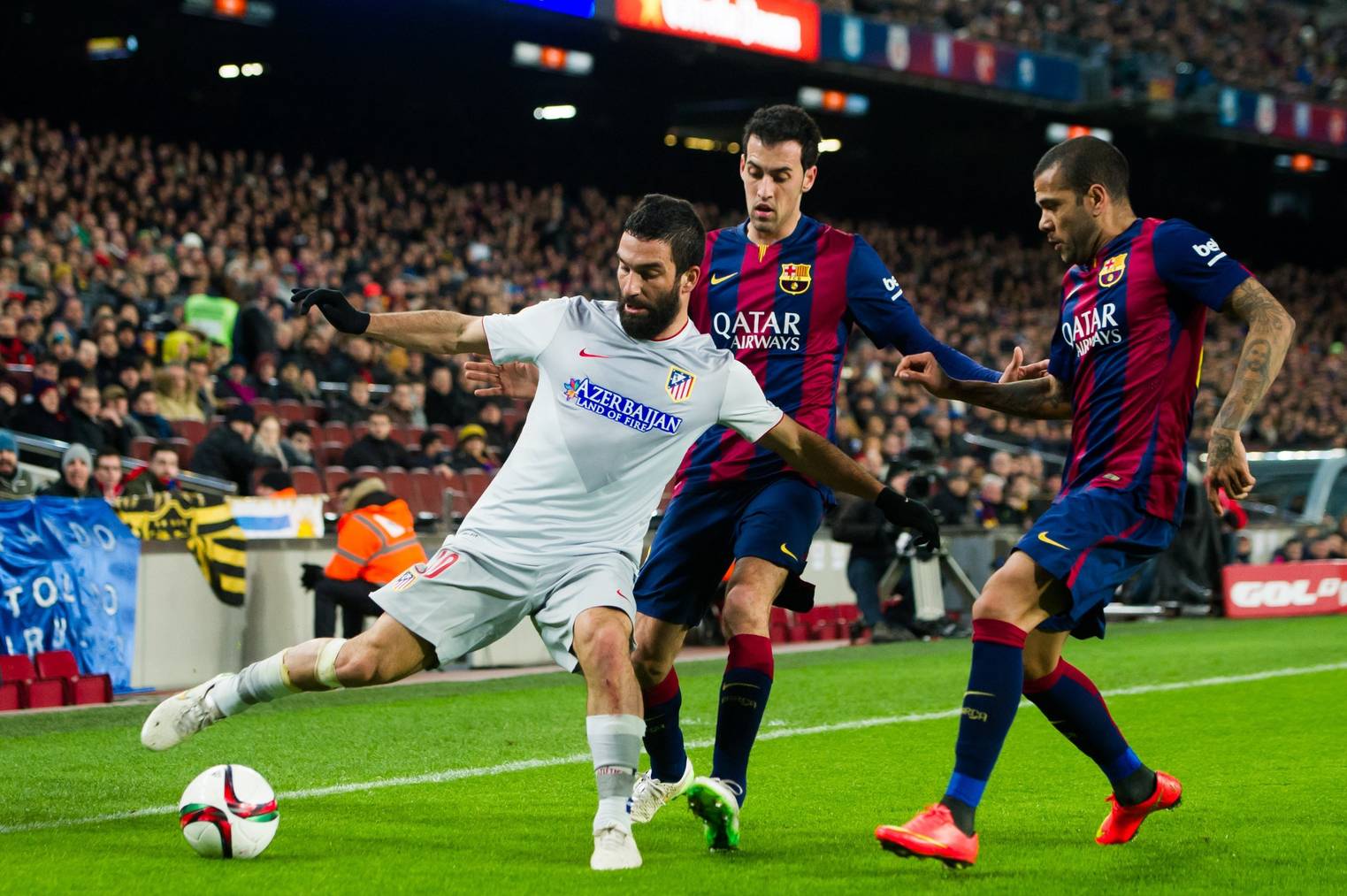 BARCELONA, SPAIN - JANUARY 21:  Arda Turan of Club Atletico de Madrid controls the ball next to Sergio Busquets (C) and Dani Alves (R) of FC Barcelona during the Copa del Rey Quarter-Final First Leg match between FC Barcelona and Club Atletico de Madrid at Camp Nou on January 21, 2015 in Barcelona, Spain. (Photo by Alex Caparros/Getty Images)