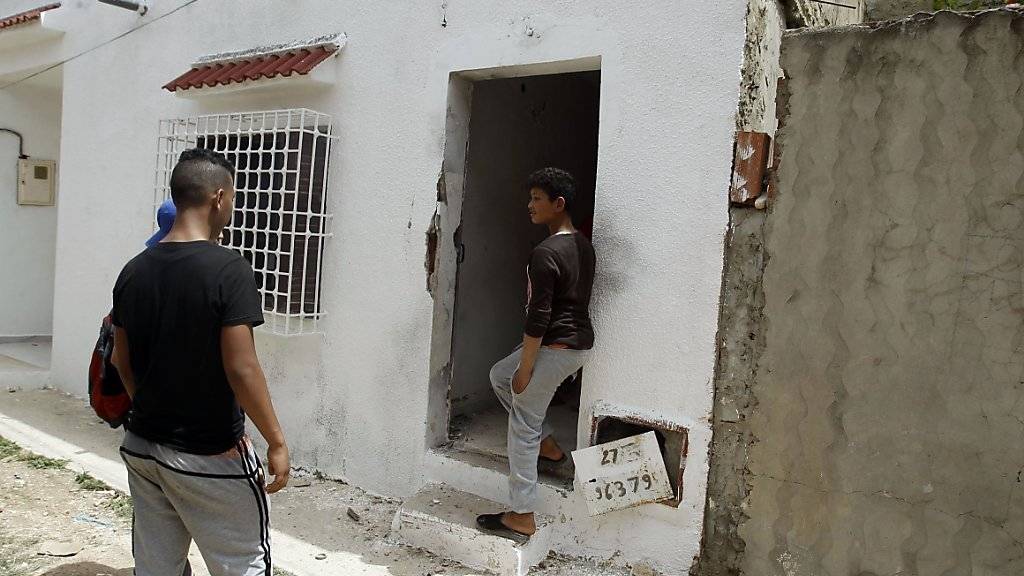 Anwohner versammeln sich bei einem Haus in Tunis, in dem Eliteeinheiten der tunesischen Polizei zwei mutmassliche Terroristen töteten. Die Polizei fand Waffen und Munition.