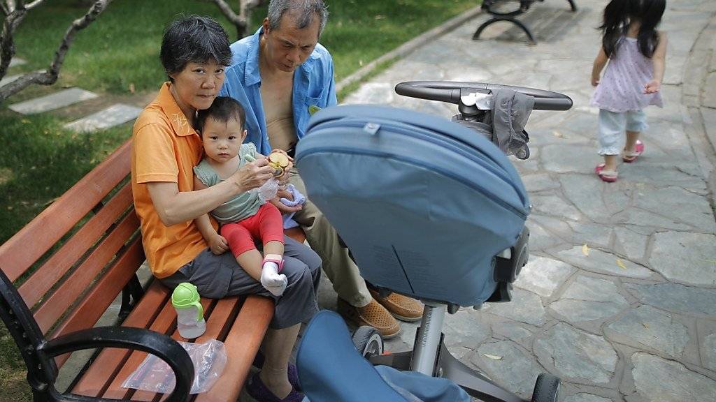 Ein kleines Kind mit älteren Betreuern in einem Park in Peking. (Archivbild)