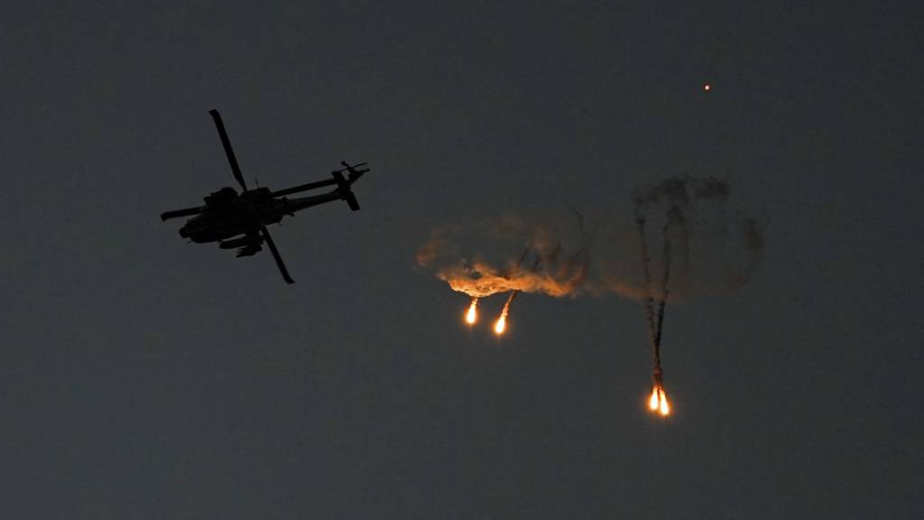 Ein israelischer Apache-Hubschrauber feuert vom Süden Israels aus gesehen Leuchtraketen über dem Gazastreifen ab. Foto: Ariel Schalit/AP/dpa