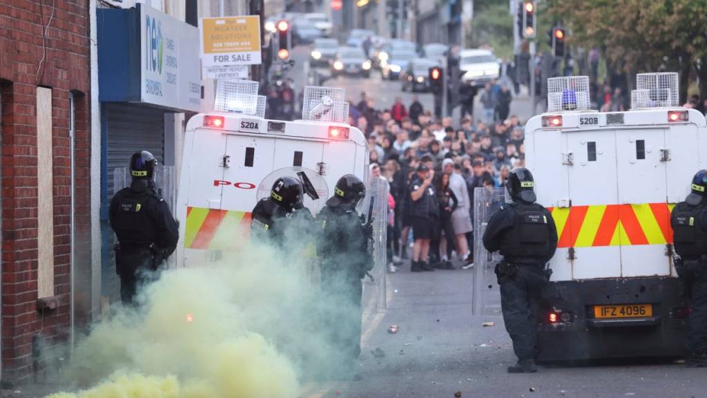 Eine gelbe Fackel raucht, nachdem sie von der Menge in Ballymena, Nordirland, auf die Polizei geworfen wurde. Foto: Peter Morrison/AP/dpa
