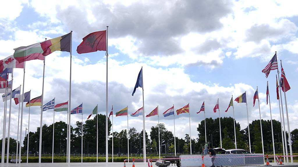 Ein Mann führt Bauarbeiten rund um die Flaggen im Nato-Hauptquartier durch. Die Nato bereitet für den bevorstehenden Gipfel in Litauen ein umfassendes Unterstützungspaket für die Ukraine vor. Foto: Virginia Mayo/AP/dpa
