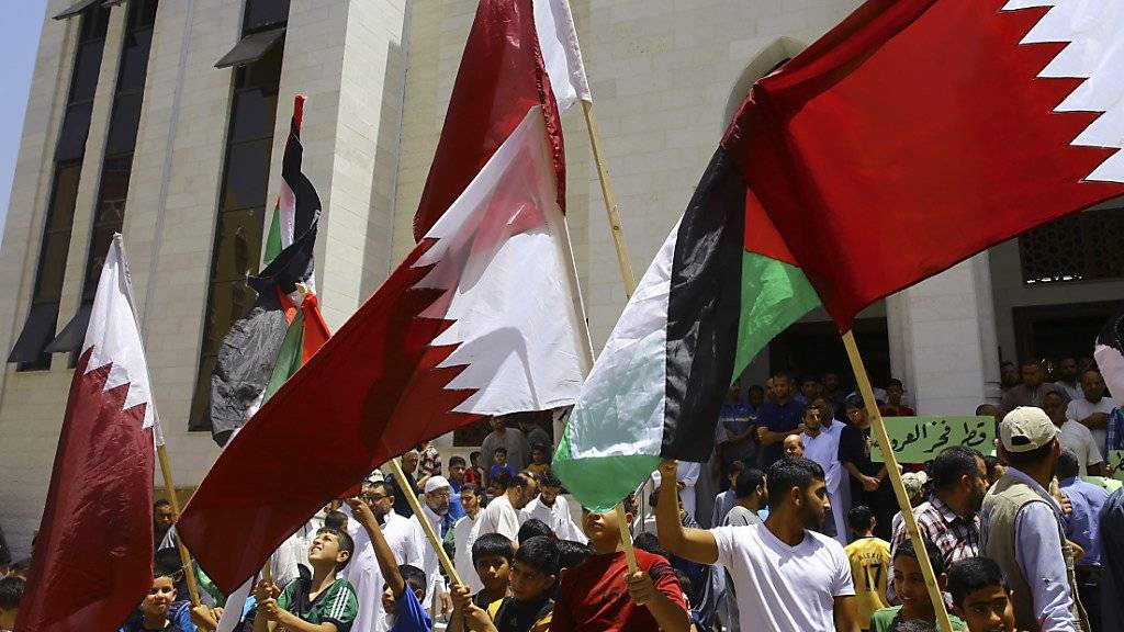 Solidaritäts-Kundgebung für Katar im Gazastreifen. Demonstranten mit der weinrot-weissen Katar-Flagge sowie der palästinensischen Flagge