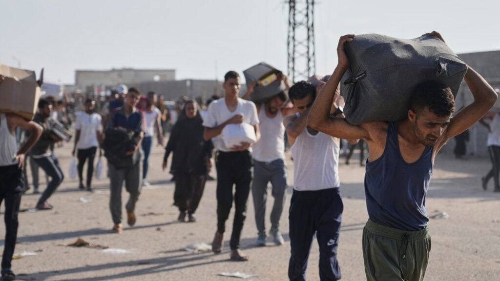 Palästinenser tragen in Rafah im südlichen Gazastreifen Kisten mit Lebensmitteln und humanitären Hilfspaketen. Foto: Abdel Kareem Hana/AP/dpa