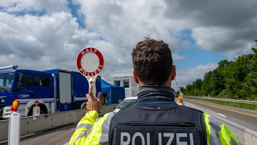 Ein deutscher Bundespolizist hält auf der A64 mit einer Kelle ein Fahrzeug an. (Archivbild)