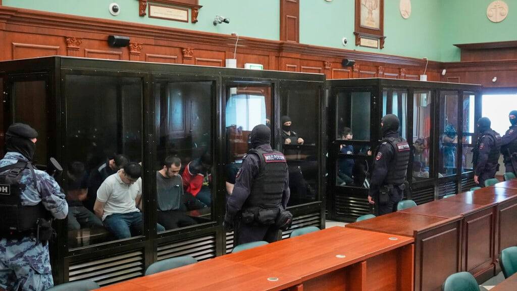Verdächtige, die beschuldigt werden, an dem  islamistischen Terroranschlag auf eine Moskauer Konzerthalle mit mehr als 140 Toten am 22. März 2024 beteiligt gewesen zu sein, sitzen in einem Glaskäfig vor einer Anhörung vor dem Militärgericht des 2. westlichen Bezirks in Moskau. Foto: Pavel Bednyakov/AP/dpa