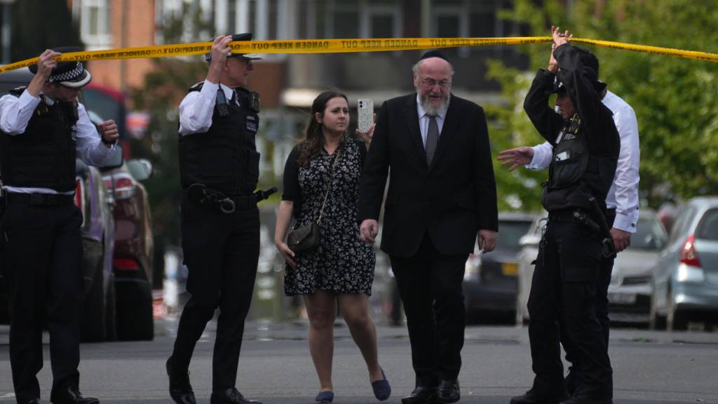 Polizeibeamte öffnen die Absperrung für den Oberrabbiner Ephraim Mirvis, nachdem zwei Menschen im Stadtteil Golders Green bei einem Messerangriff verletzt wurden. Foto: Kin Cheung/AP/dpa